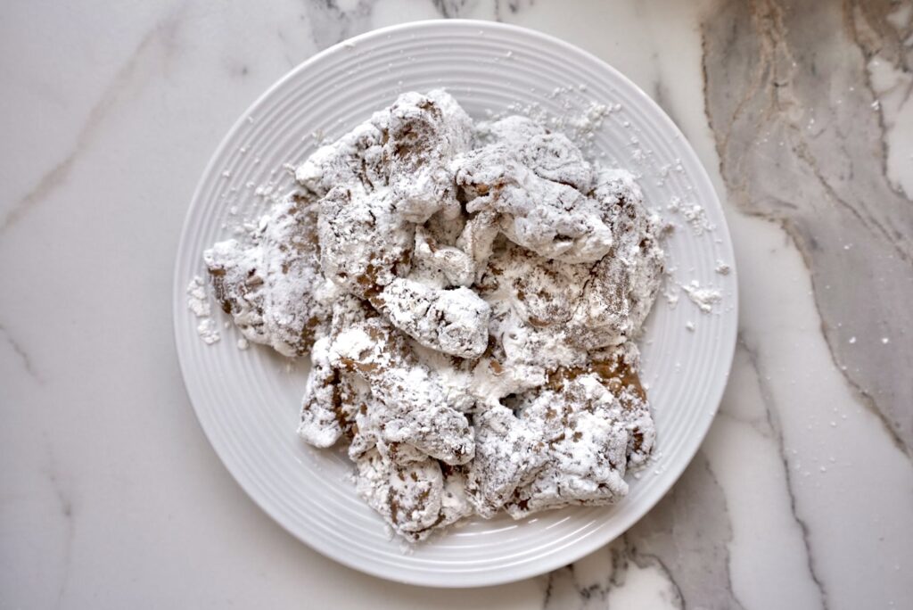 A white plate filled with curry-flavored karaage (Japanese fried chicken), generously coated in a white flour or starch mixture, placed on a marble countertop.