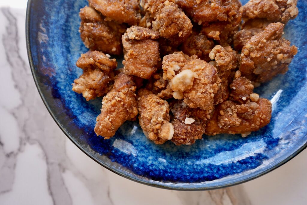 Curry‑seasoned Japanese fried chicken pieces served on a vibrant blue plate, showcasing crispy golden karaage with curry flavor.

