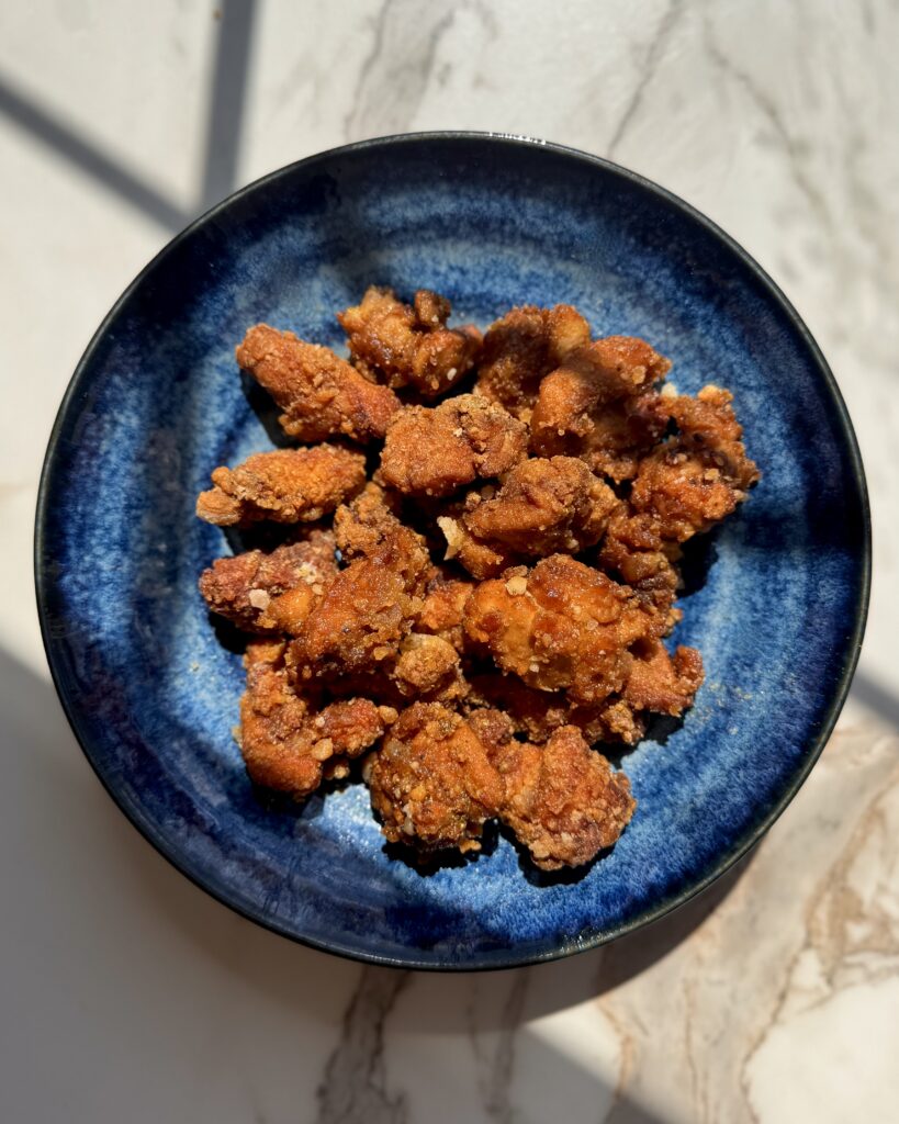 Overhead view of curry karaage arranged on a blue plate with rice and cabbage, illustrating a complete curry‑flavored Japanese fried chicken meal.

